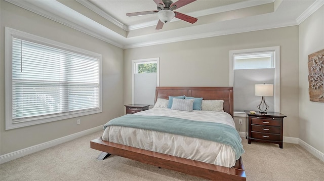 bedroom featuring baseboards, a tray ceiling, ceiling fan, ornamental molding, and light carpet