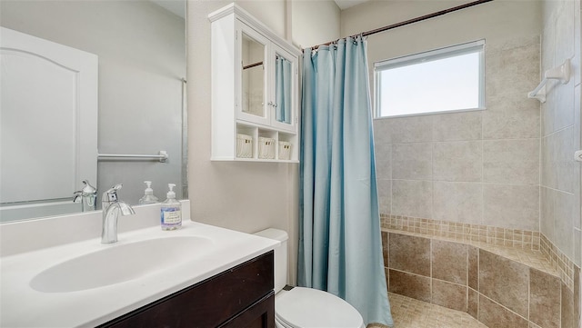 bathroom featuring vanity, toilet, and tiled shower