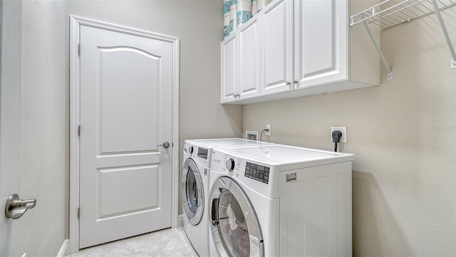 laundry area featuring cabinet space, light tile patterned floors, and washer and dryer