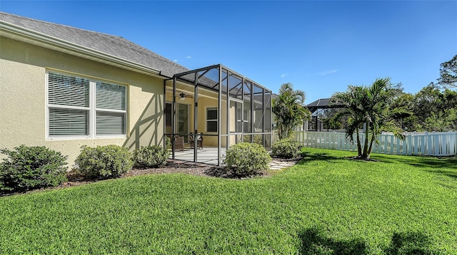 view of yard featuring a patio area, glass enclosure, ceiling fan, and fence