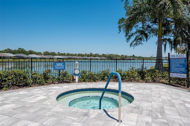 view of swimming pool with a community hot tub, a water view, and fence