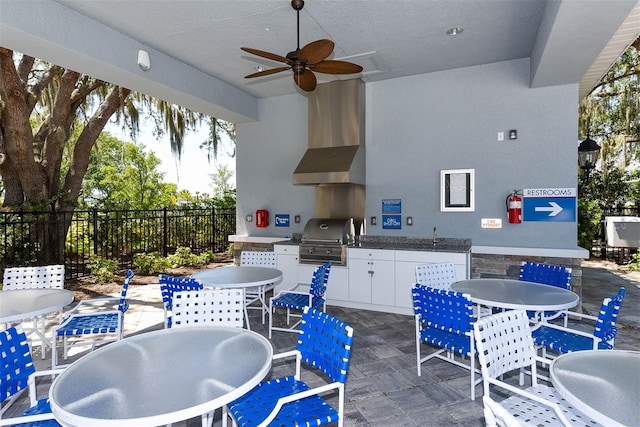 view of patio / terrace featuring grilling area, ceiling fan, fence, exterior kitchen, and outdoor dining area