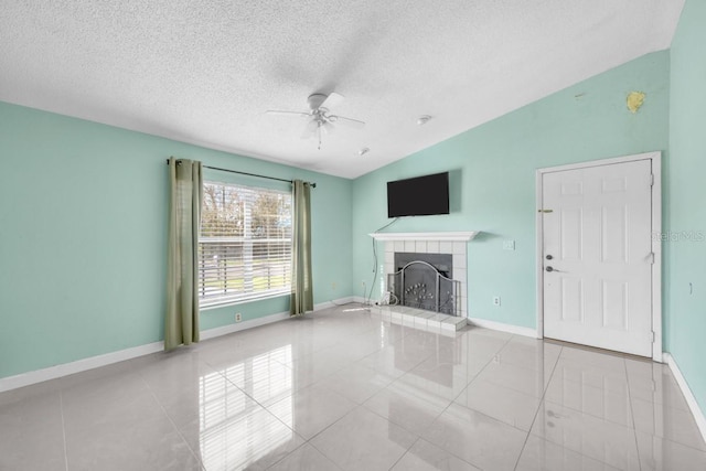 unfurnished living room featuring ceiling fan, vaulted ceiling, a tiled fireplace, and tile patterned floors