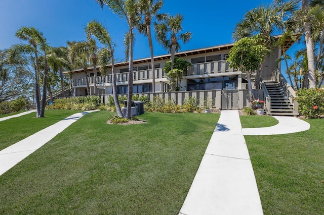 view of property's community with stairway and a lawn