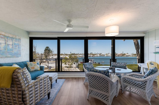 sunroom featuring a wealth of natural light, a water view, and a ceiling fan