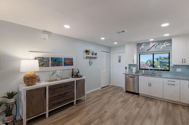 kitchen with visible vents, a sink, backsplash, white cabinets, and dishwasher