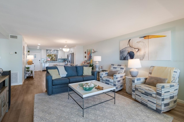 living area with visible vents, baseboards, and light wood finished floors