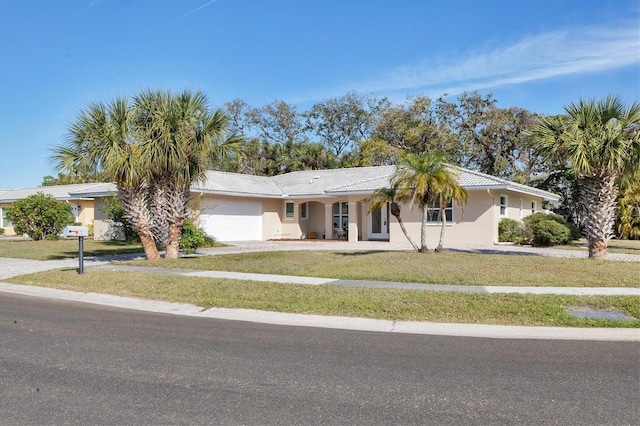 ranch-style home featuring a garage, stucco siding, driveway, and a front yard