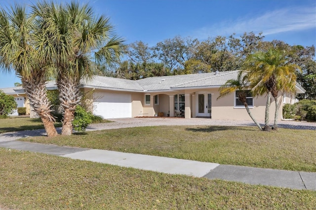 ranch-style home with a front lawn, french doors, a garage, and stucco siding