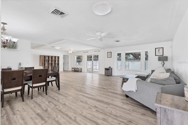 living area featuring visible vents, ceiling fan with notable chandelier, and light wood-type flooring