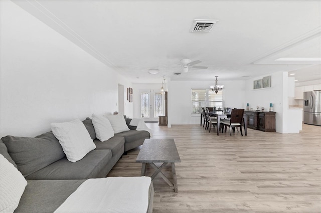 living area with light wood-type flooring, visible vents, and ceiling fan with notable chandelier