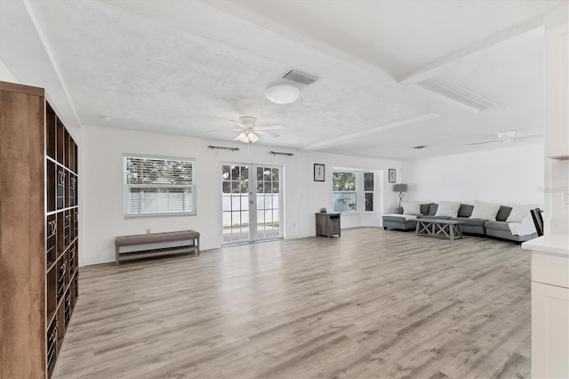 unfurnished living room featuring light wood-type flooring, visible vents, a ceiling fan, a textured ceiling, and french doors