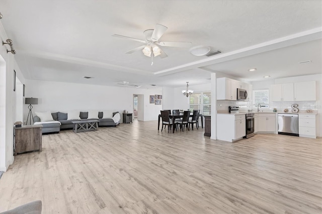 living room featuring visible vents, ceiling fan with notable chandelier, and light wood finished floors