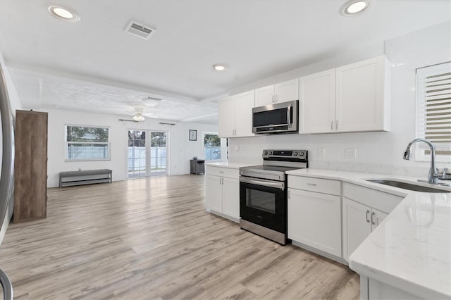 kitchen with visible vents, a sink, stainless steel appliances, white cabinets, and light wood finished floors