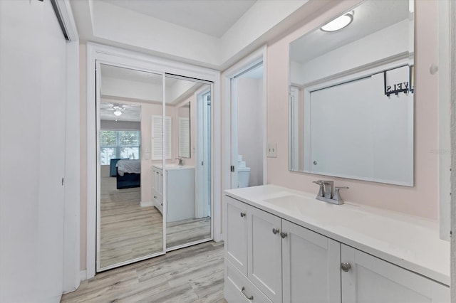 ensuite bathroom featuring baseboards, wood finished floors, ensuite bath, and vanity