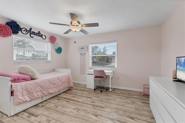 bedroom featuring baseboards, multiple windows, and light wood finished floors