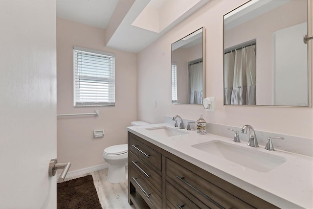 full bath with double vanity, toilet, baseboards, and a sink