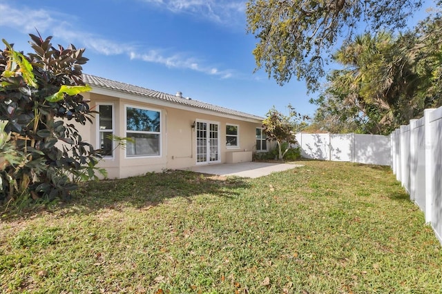 rear view of property with a patio, a lawn, a fenced backyard, and stucco siding