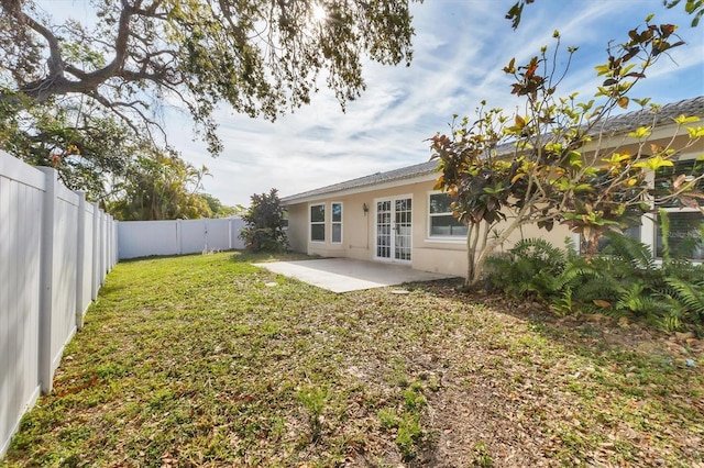 rear view of house with a patio area, stucco siding, a lawn, and a fenced backyard