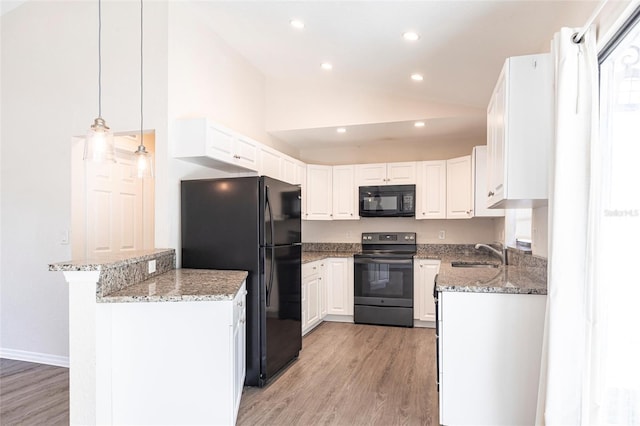 4659 Alligator Dr, Venice, FL 34293 - kitchen with a peninsula, a sink, black appliances, white cabinets, and vaulted ceiling