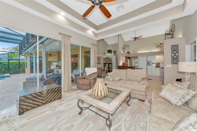 living area featuring a high ceiling, a ceiling fan, and visible vents