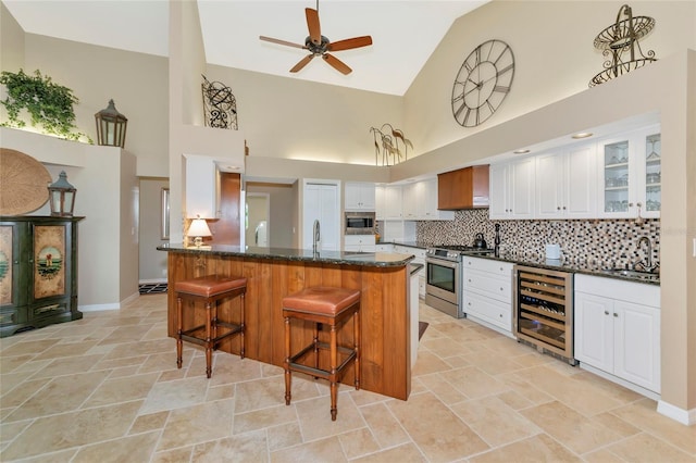 kitchen featuring tasteful backsplash, beverage cooler, a kitchen bar, stainless steel appliances, and a sink