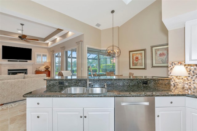 kitchen with dishwasher, dark stone counters, decorative backsplash, a fireplace, and a sink