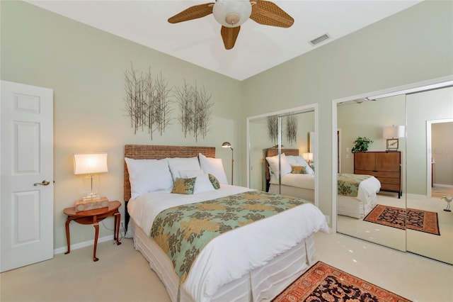 carpeted bedroom featuring a ceiling fan, visible vents, two closets, and baseboards