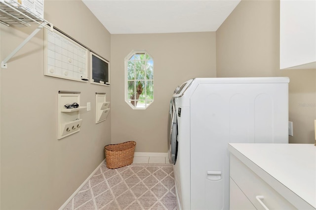 laundry room featuring cabinet space, light tile patterned flooring, washing machine and dryer, and baseboards