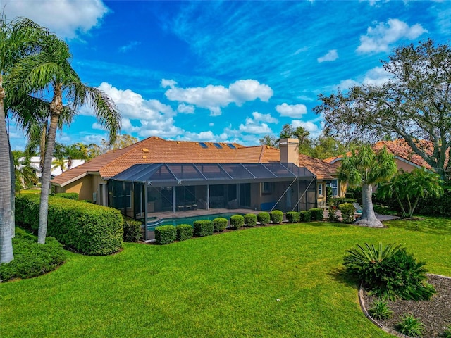 back of house featuring a lanai, a lawn, and a chimney