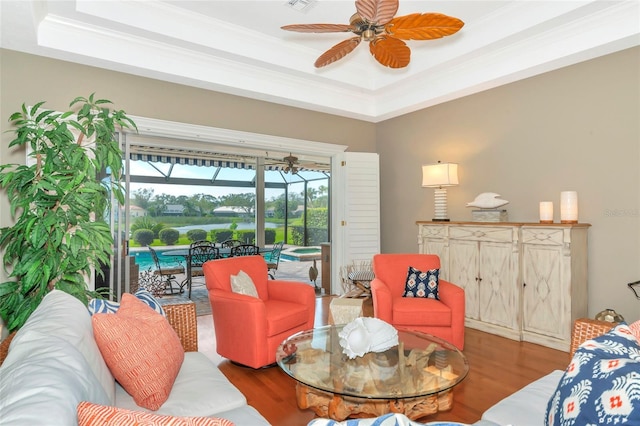 living area featuring crown molding, ceiling fan, a sunroom, wood finished floors, and a raised ceiling