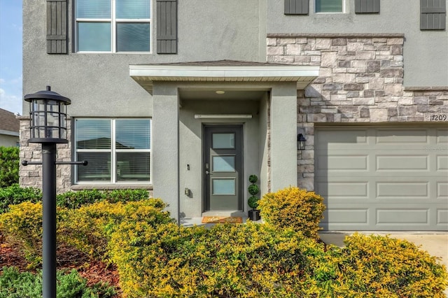 entrance to property with stone siding, stucco siding, and a garage