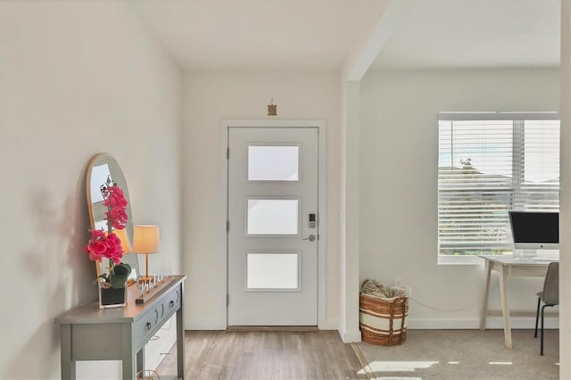 foyer entrance featuring a wealth of natural light, light wood-type flooring, and baseboards