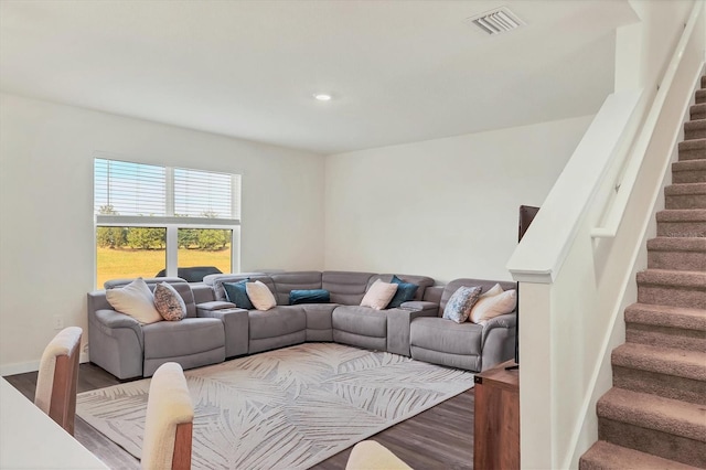 living area with visible vents, stairs, baseboards, and wood finished floors