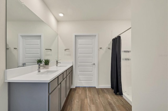 full bath featuring double vanity, wood finished floors, a stall shower, and a sink