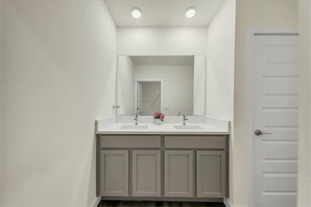 bathroom with double vanity, baseboards, and a sink