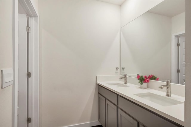 full bath featuring double vanity, baseboards, and a sink