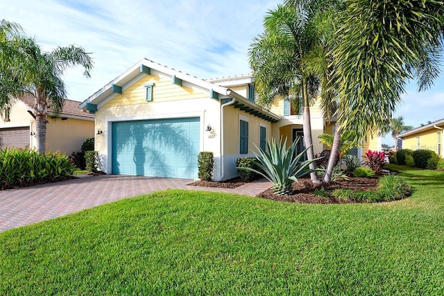 view of front facade with stucco siding, a front yard, decorative driveway, and a garage