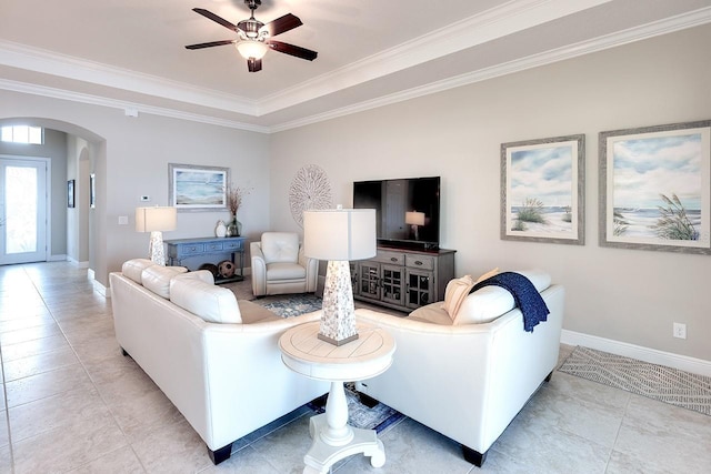 living area featuring arched walkways, ceiling fan, baseboards, and ornamental molding