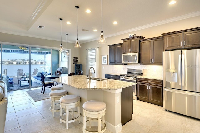 kitchen with visible vents, a sink, backsplash, appliances with stainless steel finishes, and light stone countertops