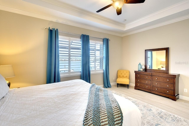 bedroom with a raised ceiling, a ceiling fan, wood finished floors, crown molding, and baseboards