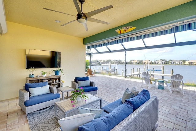 view of patio with glass enclosure, ceiling fan, a water view, and an outdoor hangout area