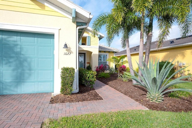 property entrance featuring a garage and stucco siding