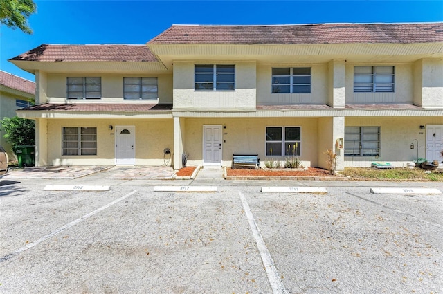 view of property featuring stucco siding, uncovered parking, and a porch