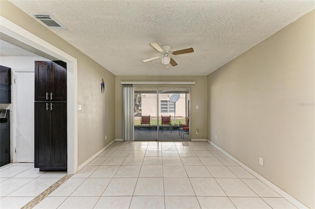 spare room featuring light tile patterned flooring, visible vents, baseboards, and ceiling fan