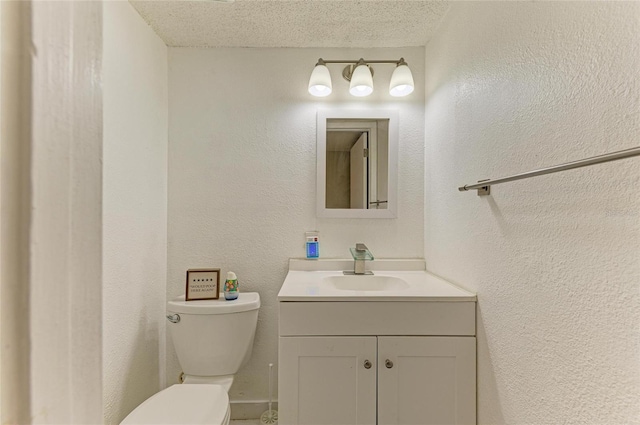 bathroom featuring a textured ceiling, toilet, vanity, and a textured wall