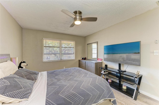 bedroom featuring baseboards, a textured ceiling, a ceiling fan, and wood finished floors