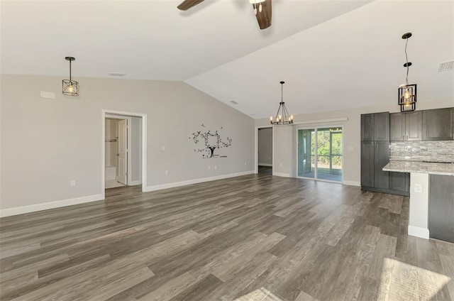 unfurnished living room with baseboards, dark wood finished floors, vaulted ceiling, and ceiling fan with notable chandelier