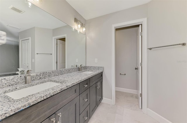 bathroom featuring double vanity, baseboards, visible vents, and a sink