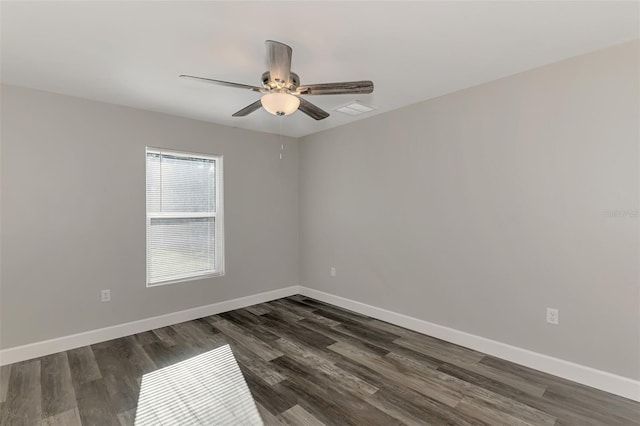 spare room featuring dark wood finished floors, visible vents, a ceiling fan, and baseboards